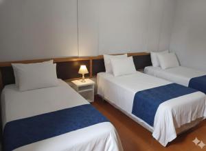 a room with two beds and a table with a lamp at Gutemberg Palace Hotel in Nova Serrana