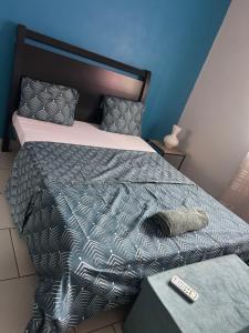 a bed with a comforter and a remote control on it at Le Donjon du lycée in Sada