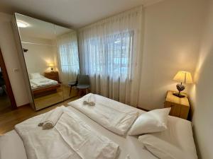 a bedroom with a bed with white sheets and a mirror at Central Dolomites Atelier - 3 Bedrooms in Campitello di Fassa