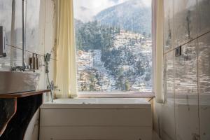 a bathroom with a window with a view of a mountain at Sunrise Farm Stays in Jibhi +192 photos