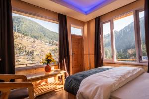 a bedroom with a bed and large windows with a view at Sunrise Farm Stays in Jibhi
