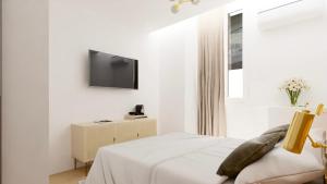 a white bedroom with a bed and a tv on a wall at Hotel le Romanesque in Cannes