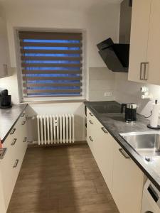 a kitchen with white cabinets and a window with a radiator at Am Biebricher Schloßpark in Wiesbaden