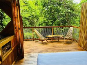 a porch with two chairs and a table on it at Pura selva tree house in Tamarindo