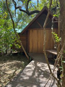 a wooden cabin with a bench on a wooden deck at Pura selva tree house in Tamarindo