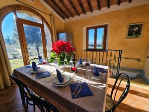 a dining room table with red flowers and wine glasses at Villa S.Anna in Montisi
