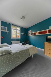 a bedroom with a bed and a blue wall at Maison Grillon - Maison proche de Vichy avec piscine in Abrest +30 photos