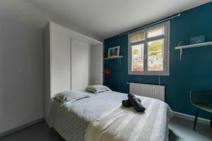 a bedroom with a bed and a blue wall at Maison Grillon - Maison proche de Vichy avec piscine in Abrest
