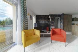two yellow and orange chairs in a living room at Maison Grillon - Maison proche de Vichy avec piscine in Abrest