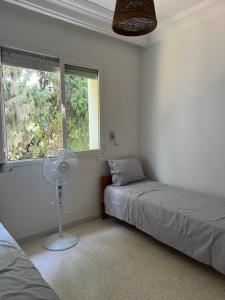 a bedroom with two beds and a fan and a window at Ecume et Sérénité in Monastir