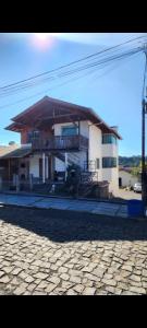 a large house with a balcony on a cobblestone street at Hospedaria Klagemberg in Treze Tílias