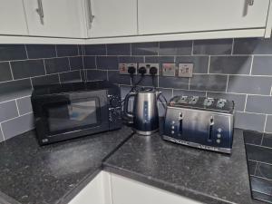 a kitchen counter with a toaster and a microwave at New Guest House, Individual Ensuite Rooms with Comfortable Double Beds, TV and WiFi in Luton