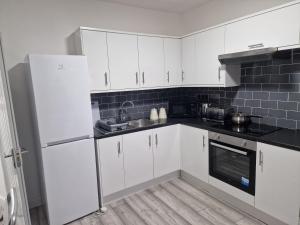 a kitchen with white cabinets and a sink at New Guest House, Individual Ensuite Rooms with Comfortable Double Beds, TV and WiFi in Luton +54 photos
