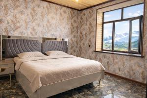a bedroom with a bed and a window and mountains at Shahdag Cozy House in Qusar +10 photos