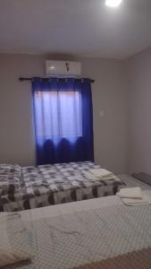a bedroom with a bed with a blue curtain at Hotel Ypê in Floriano