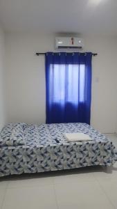 a bed in a room with a blue curtain at Hotel Ypê in Floriano