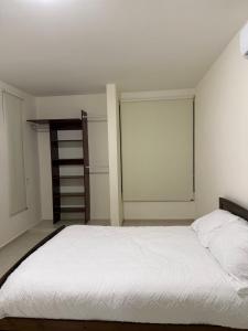 a bedroom with a white bed and a book shelf at Casa completa , dos Habitaciones con baño en cada cuarto in Mérida +8 photos
