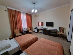 a hotel room with two beds and a television at GRAND STAR HOTEL in Qarshi