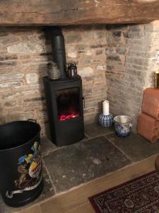 a brick fireplace with a stove in a room at Logaston Common Farmhouse in Woonton