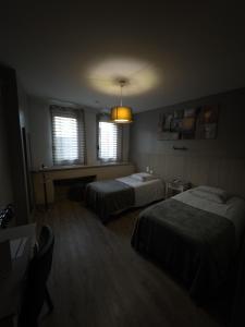 a hotel room with two beds and a light at Hôtel le midi in Montaigu-de-Quercy