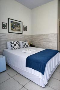 a bedroom with a large white bed with a blue blanket at Pousada 2 Rios Comfort in Barra do Garças