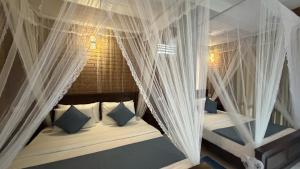 a bedroom with two beds with white curtains and pillows at Evergreen Cottage in Ella