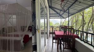 a room with a table and chairs on a balcony at Evergreen Cottage in Ella