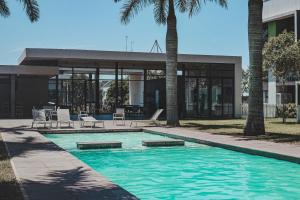 a swimming pool in front of a building with palm trees at Ballito Exotic Lifestyle in Ballito