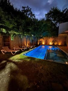 a swimming pool with lights in a backyard at night at condo pacha tulum in Tulum
