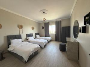 a bedroom with three beds and a mirror at شاليه درة العروس in Durat Alarous