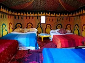 a bedroom with two beds and a wall with pictures on it at Desert Berber Fire-Camp in Merzouga
