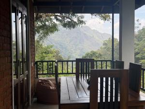 a porch with two chairs and a view of a mountain at Evergreen Cottage in Ella
