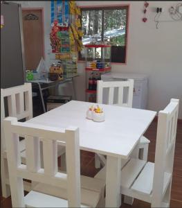 a white dining table and chairs in a kitchen at Cafeteria y cabañas Eluney - Koigue in Pucón