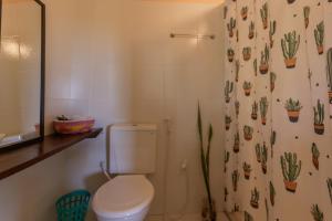 a bathroom with a toilet and a shower curtain with cactus at Chalé Pé de Araçá - Massarandupió in Entre Rios