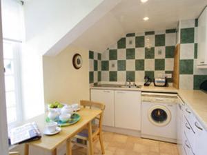 a kitchen with a table and a washing machine at Rosecraddoc Manor - Heron in Saint Cleer