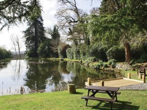 a picnic table in front of a pond with a bench at Rosecraddoc Manor - Heron in Saint Cleer