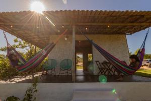 two people sitting in hammocks under a pergola at Chalé Pé de Araçá - Massarandupió in Entre Rios