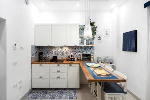 a kitchen with white cabinets and a wooden counter top at Le Pupatelle Apartment in Castellammare di Stabia