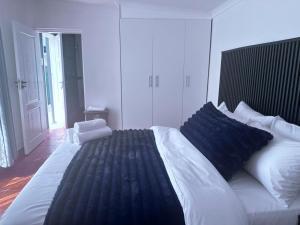 a bedroom with a large white bed with blue pillows at SA Guest House in Roodepoort +57 photos