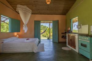 a bedroom with a bed and a kitchen in it at Chalé Pé de Araçá - Massarandupió in Entre Rios