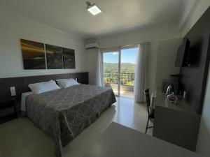 a bedroom with a bed and a view of a balcony at Hotel Queijo & Cia in Capão Alto