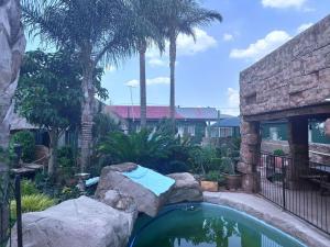 a swimming pool in a yard with rocks and trees at SA Guest House in Roodepoort