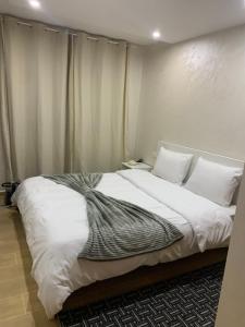 a bedroom with a large bed with white sheets and pillows at bel appartement juste à côté de McDonald's in Kenitra