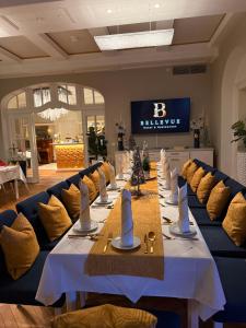 a long table in a room with blue couches and a table with yellow nap at Hotel & Restaurant Bellevue Schmölln in Schmölln