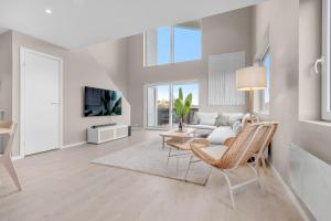 a white living room with a couch and a tv at Sunset Bay Penthouse in Kristiansand