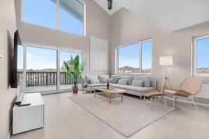 a living room with a couch and a tv and windows at Sunset Bay Penthouse in Kristiansand