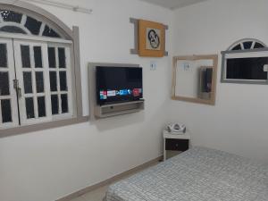 a bedroom with a bed and a tv on a wall at Microcasa loft in São Pedro da Aldeia
