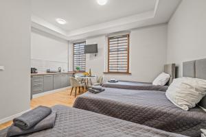 a bedroom with two beds and a kitchen with a table at Central Platinum Apartments 2 Studio z aneksem kuchennym 3 łóżka in Rybnik