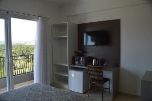 a bedroom with a bed and a balcony with a tv at Hotel Queijo & Cia in Capão Alto +16 photos
