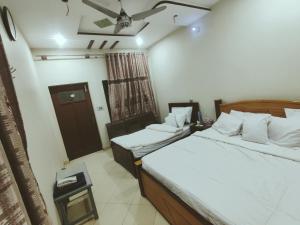 a hotel room with two beds and a window at Al Hidayah Hotel Multan in Multan